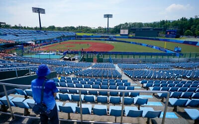 A steward watches from the empty grandstands during the softball game between Japan and Australia at the 2020 Summer Olympics, July 21, 2021, in Fukushima, Japan. (AP/Jae C. Hong)