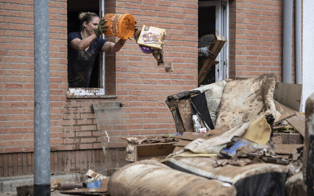 A woman throws rubbish from the window of her home onto a pile of discarded goods in the district of Blessem, in Ergfstadt, Germany, Thursday July 22, 2021. In the flood disaster area of Erftstadt-Blessem, some residents are being allowed back into their homes to clear debris after heavy rains caused devastating floods. (Marius Becker/dpa via AP) A woman throws rubbish from the window of her home onto a pile of discarded goods in the district of Blessem, in Ergfstadt, Germany, Thursday July 22, 2021. In the flood disaster area of Erftstadt-Blessem, some residents are being allowed back into their homes to clear debris after heavy rains caused devastating floods. (Marius Becker/dpa via AP)
