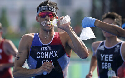 Dorian Coninx of France takes water as a volunteer holds out a bag of ice, during the run portion of the men's individual triathlon at the 2020 Summer Olympics, July 26, 2021, in Tokyo, Japan. (AP Photo/Jae C. Hong)