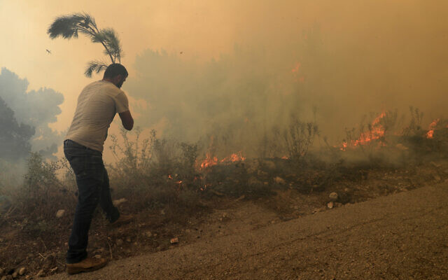 A man tries to extinguish g a forest fire, at Qobayat village, in the northern Akkar province, Lebanon, July 29, 2021. (Hussein Malla/AP) A man tries to extinguish g a forest fire, at Qobayat village, in the northern Akkar province, Lebanon, July 29, 2021. (Hussein Malla/AP)