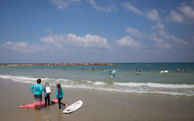 Illustrative -- Young children learning to surf at a beach in Tel Aviv, on a hot summer day, July 30, 2018 (Miriam Alster/FLASH90)