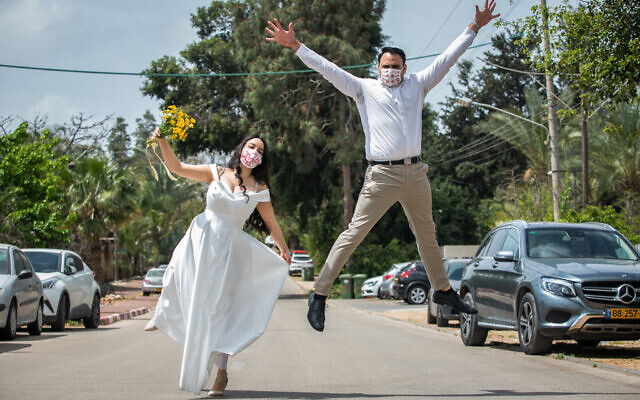 Gal Sade Knigsfild and Nofar Almakias pose for a picture with face mask before their wedding in Moshav Yashresh on April 6, 2020. (Yossi Aloni/Flash90) Gal Sade Knigsfild and Nofar Almakias pose for a picture with face mask before their wedding in Moshav Yashresh on April 6, 2020. (Yossi Aloni/Flash90)