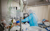 Shaare Zedek Medical Center staff wearing protective clothes move patients to the new coronavirus ward of the hospital in Jerusalem, on January 7, 2021. (Olivier Fitoussi/Flash90)
