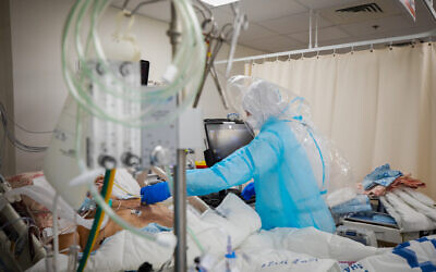 Shaare Zedek Medical Center staff wearing protective clothes move patients to the new coronavirus ward of the hospital in Jerusalem, on January 7, 2021. (Olivier Fitoussi/Flash90)