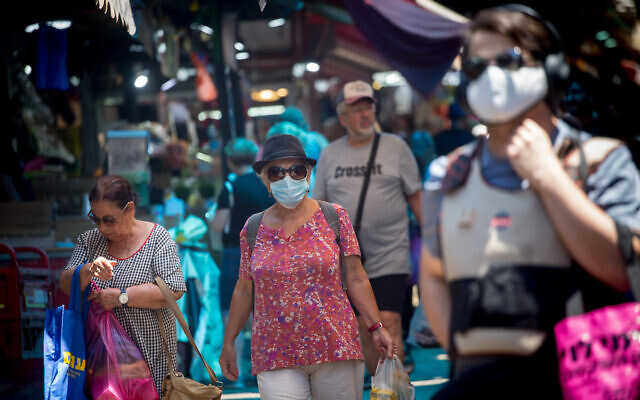 Israelis, some wearing face masks, walk through the Carmel Market in Tel Aviv on July 5, 2021. (Miriam Alster/Flash90) Israelis, some wearing face masks, walk through the Carmel Market in Tel Aviv on July 5, 2021. (Miriam Alster/Flash90)
