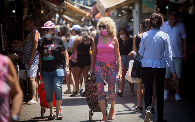 Israelis wear protective face masks as they walk through the Carmel market in Tel Aviv, on July 5, 2021. (Miriam Alster/FLASH90) Israelis wear protective face masks as they walk through the Carmel market in Tel Aviv, on July 5, 2021. (Miriam Alster/FLASH90)