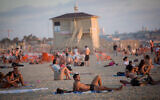 Israelis enjoy the beach in Tel Aviv on a hot summer day, on July 6, 2021. (Miriam Alster/Flash90)