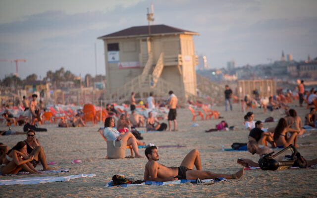 Israelis enjoy the beach in Tel Aviv on a hot summer day, on July 6, 2021. (Miriam Alster/Flash90)