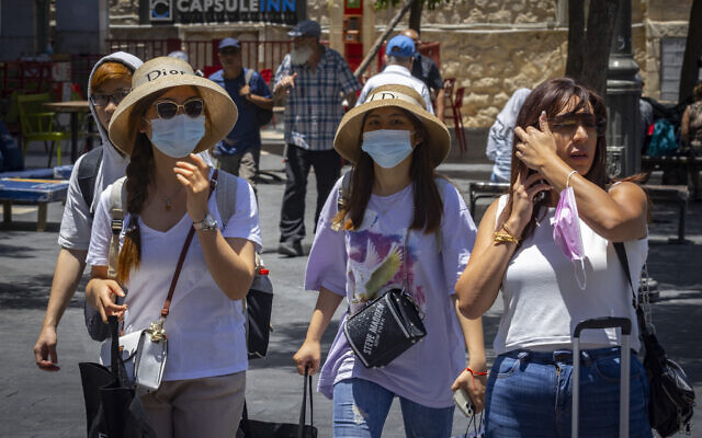 People, some with face masks, walk in Jerusalem on July 12, 2021. (Olivier Fitoussi/Flash90) People, some with face masks, walk in Jerusalem on July 12, 2021. (Olivier Fitoussi/Flash90)