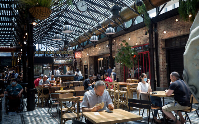 People eating at Sarona market in Tel Aviv on July 13, 2021. (Miriam Alster/FLASH90)