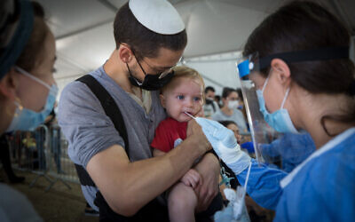 A technician collects a swab sample for COVID-19, at a testing center in Tel Aviv (Miriam Alster/Flash90)