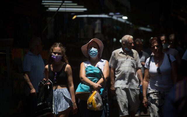 Israelis, some wearing face masks, as they walk through the Carmel Market in Tel Aviv on July 20, 2021. (Miriam Alster/Flash90) Israelis, some wearing face masks, as they walk through the Carmel Market in Tel Aviv on July 20, 2021. (Miriam Alster/Flash90)