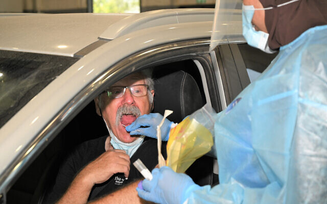 A healthcare worker takes a swab sample from a man at a drive-thru coronavirus testing site in the Golan Heights, on July 30, 2021. (Michael Giladi/Flash90) A healthcare worker takes a swab sample from a man at a drive-thru coronavirus testing site in the Golan Heights, on July 30, 2021. (Michael Giladi/Flash90)