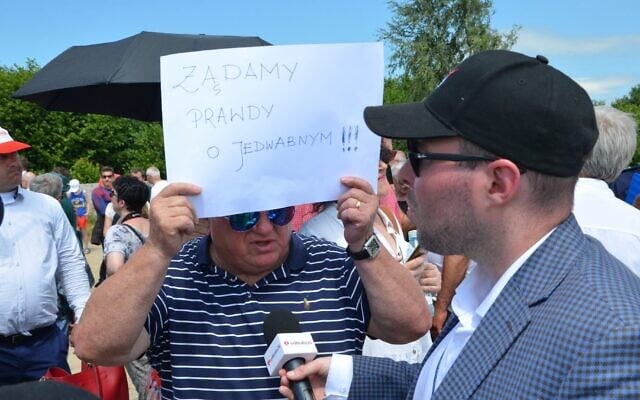 A Polish nationalist holds a sign reading "We demand the truth about Jedwabne," at the site of a Holocaust pogrom in Jedwabne, Poland, on July 10, 2021. (Krzysztof Bielawski) A Polish nationalist holds a sign reading "We demand the truth about Jedwabne," at the site of a Holocaust pogrom in Jedwabne, Poland, on July 10, 2021. (Krzysztof Bielawski)