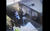A screenshot of security camera footage shows suspects vandalizing posters of the victims of the Mount Meron disaster. (Screen capture: Twitter)