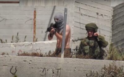 A photo distributed by B'Tselem showing an off-duty soldier with a shirt wrapped around his face as a mask opening fire toward the village of Urif from the Yitzhar settlement on May 14, 2021. (B'Tselem)