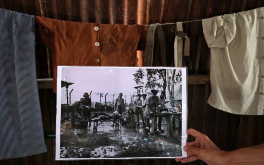 A man holds an old picture of Jews detained by British soldiers in Cyprus washing clothes at the camp, at the Jewish museum of Cyprus in the port city of Larnaca on July 26, 2021. (Christina ASSI / AFP)