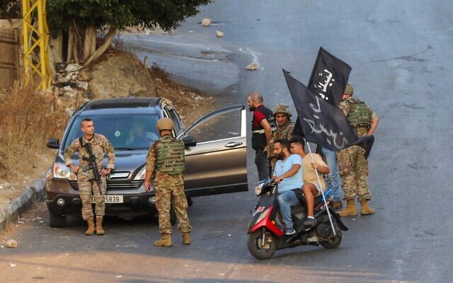 Hezbollah supporters carrying flags on motorbikes drive past Lebanese soldiers as the army deploys amid clashes in the Khalde area, south of the capital, on August 1, 2021 (ANWAR AMRO / AFP) Hezbollah supporters carrying flags on motorbikes drive past Lebanese soldiers as the army deploys amid clashes in the Khalde area, south of the capital, on August 1, 2021 (ANWAR AMRO / AFP)