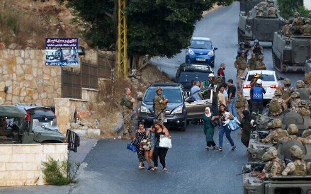People are evacuated as Lebanese soldiers deploy in armored vehicles amid clashes in the Khalde area, south of the capital, on August 1, 2021. - At least five people including three Hezbollah members were killed south of Beirut when a funeral procession for a party member was ambushed(Photo by ANWAR AMRO / AFP)