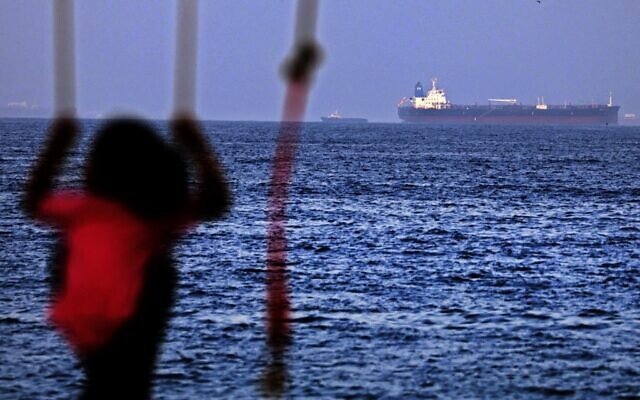 A child rides a swing as the Israeli-linked Japanese-owned tanker MT Mercer Street is seen off the port of the Gulf Emirate of Fujairah in the United Arab Emirates on August 3, 2021 (Karim SAHIB / AFP) A child rides a swing as the Israeli-linked Japanese-owned tanker MT Mercer Street is seen off the port of the Gulf Emirate of Fujairah in the United Arab Emirates on August 3, 2021 (Karim SAHIB / AFP)