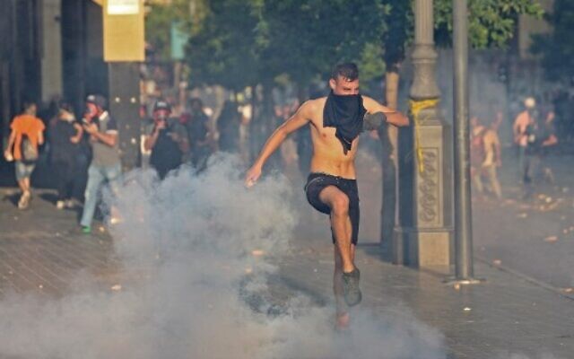 A Lebanese man kicks a teargas cannister as Lebanese army and security forces clash with demonstrators near the parliament in downtown Beirut on August 4, 2021. (AFP) A Lebanese man kicks a teargas cannister as Lebanese army and security forces clash with demonstrators near the parliament in downtown Beirut on August 4, 2021. (AFP)