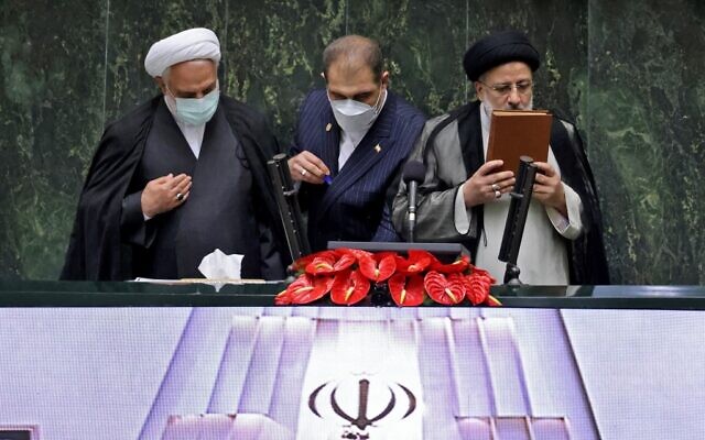 Newly elected President Ebrahim Raisi (R) kisses the Koran stand on the podium at his swearing in ceremony at the Iranian parliament in the capital Tehran on August 5, 2021. (Atta KENARE / AFP)