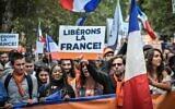 Protestors hold a French flag and a sign reading 'Liberate France' during a demonstration, part of a national day of protest against the mandatory Covid-19 health pass to access most of the public space, near Ecole Militaire in Paris on August 7, 2021. (Photo by STEPHANE DE SAKUTIN / AFP)
