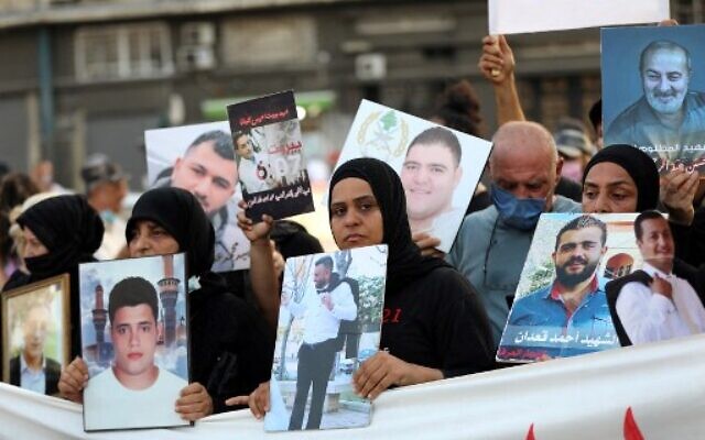 Families of the August 4 victims joined by protestors march with imitation coffins and portraits of their loved ones during a symbolic funeral procession from Beirut port on August 8, 2021, days after the first anniversary of a vast dockside explosion that left more than 200 people dead. (ANWAR AMRO / AFP) Families of the August 4 victims joined by protestors march with imitation coffins and portraits of their loved ones during a symbolic funeral procession from Beirut port on August 8, 2021, days after the first anniversary of a vast dockside explosion that left more than 200 people dead. (ANWAR AMRO / AFP)