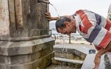 A man refreshes himself in a fountain during a hot summer day in Messina, on August 11, 2021. (Giovanni ISOLINO / AFP)