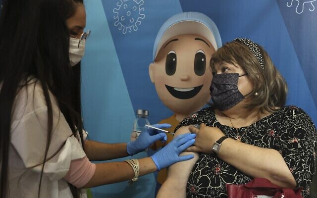 An Israeli medic administers a dose of the Pfizer-BioNTech vaccine against the coronavirus to a woman at a Clalit Health Services station set up inside Cinema City complex in Jerusalem, on August 11, 2021. (HAZEM BADER / AFP)