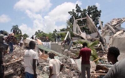 People search through the rubble of what used to be the Manguier Hotel after the earthquake hit on August 14, 2021 in Les Cayes, southwest Haiti. (Stanley LOUIS / AFP)