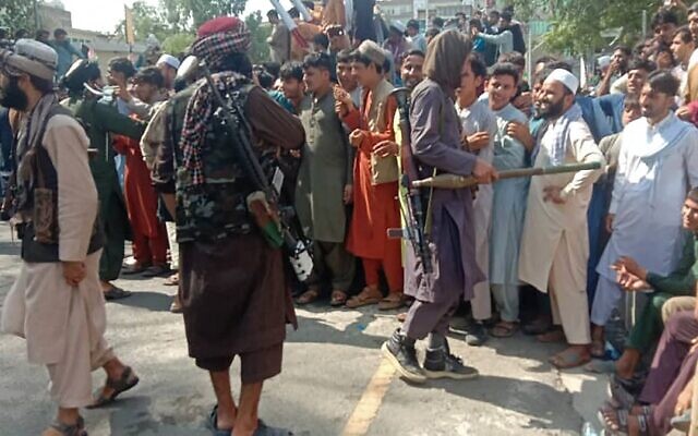 Taliban fighters and local people are pictured along the street in Jalalabad province on August 15, 2021. (AFP)
