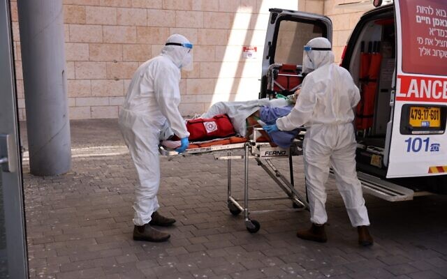Medics with Magen David Adom transfer a coronavirus patient to the Hadassah Ein Kerem Hospital in Jerusalem, due to full capacity in other hospitals, following a sharp increase in the number of coronavirus infections in Israel, on August 15, 2021. (Menahem KAHANA / AFP) Medics with Magen David Adom transfer a coronavirus patient to the Hadassah Ein Kerem Hospital in Jerusalem, due to full capacity in other hospitals, following a sharp increase in the number of coronavirus infections in Israel, on August 15, 2021. (Menahem KAHANA / AFP)
