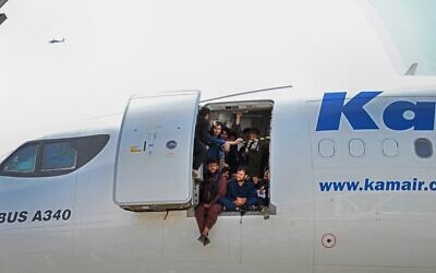 Afghan people climb up on a plane and sit by the door as they wait at the Kabul airport in Kabul on August 16, 2021 (Wakil Kohsar / AFP)