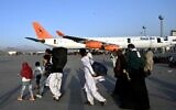 Afghan families walk by the aircrafts at the Kabul airport in Kabul on August 16, 2021, after a stunningly swift end to Afghanistan's 20-year war, as thousands of people mobbed the city's airport trying to flee the group's feared hardline brand of Islamist rule. (Wakil Kohsar / AFP)