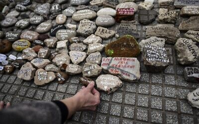 A woman places a stone with the name of a relative outside the Casa Rosada government house during the march of the stones in homage to COVID-19 victims, in Buenos Aires, Argentina, on August 16, 2021. (Ronaldo Schmeidt/AFP)