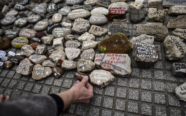 A woman places a stone with the name of a relative outside the Casa Rosada government house during the march of the stones in homage to COVID-19 victims, in Buenos Aires, Argentina, on August 16, 2021. (Ronaldo Schmeidt/AFP) A woman places a stone with the name of a relative outside the Casa Rosada government house during the march of the stones in homage to COVID-19 victims, in Buenos Aires, Argentina, on August 16, 2021. (Ronaldo Schmeidt/AFP)