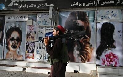 A Taliban fighter walks past a beauty salon with images of women defaced using spray paint in Shar-e-Naw in Kabul on August 18, 2021. (Wakil KOHSAR / AFP)