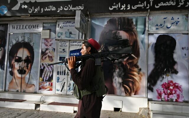 A Taliban fighter walks past a beauty salon with images of women defaced using spray paint in Shar-e-Naw in Kabul on August 18, 2021. (Wakil KOHSAR / AFP) A Taliban fighter walks past a beauty salon with images of women defaced using spray paint in Shar-e-Naw in Kabul on August 18, 2021. (Wakil KOHSAR / AFP)