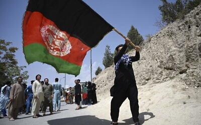 An Afghan waves the national flag in Kabul on August 19, 2021. (WAKIL KOHSAR / AFP)