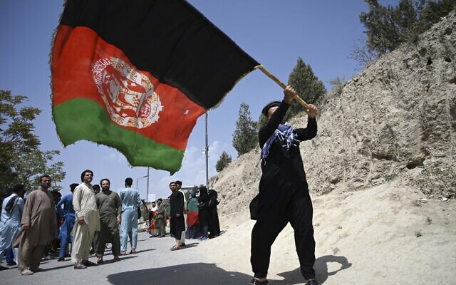 An Afghan waves the national flag in Kabul on August 19, 2021. (WAKIL KOHSAR / AFP)
