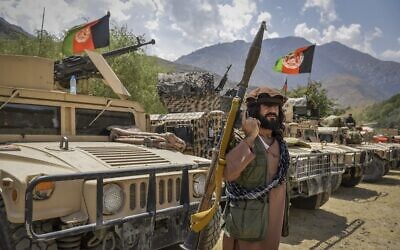 An armed Afghan man supporting the Afghan security forces against the Taliban stands next to humvees at Parakh area in Bazarak, Panjshir province, on August 19, 2021. (Ahmad Sahel Arman/AFP)