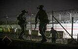 In this picture taken in the late hours on August 22, 2021, British and Canadian soldiers stand guard near a canal as Afghans wait outside the foreign military-controlled part of the airport in Kabul, hoping to flee the country following the Taliban's military takeover of Afghanistan. (Wakil Kohsar/AFP)