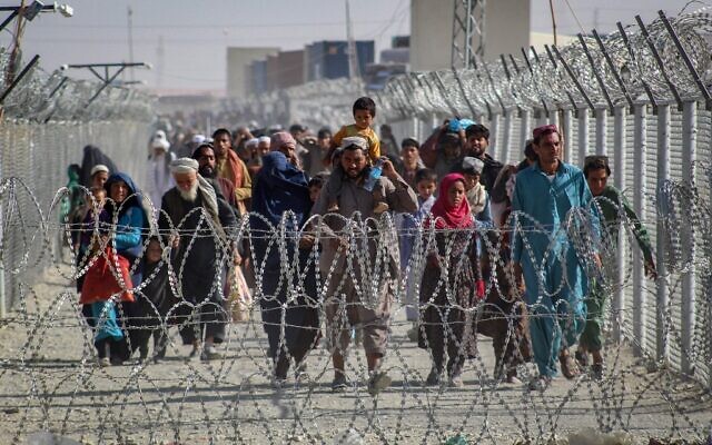 Afghans walk along fences as they arrive in Pakistan through the Pakistan-Afghanistan border crossing point in Chaman on August 24, 2021 following Taliban's military takeover of Afghanistan. (AFP)