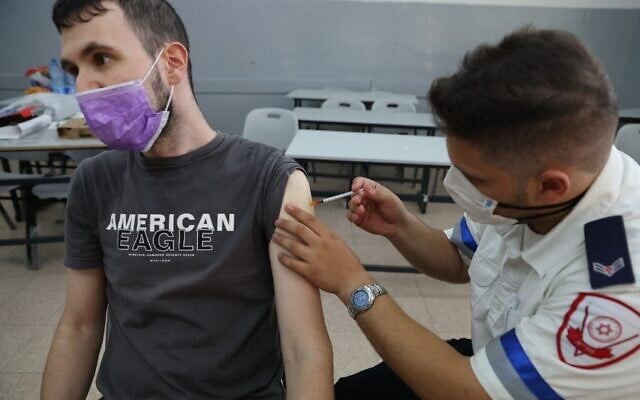 A Magen David Adom paramedic administers a third dose of the Pfizer-BioNTech COVID-19 vaccine to an Israeli man, on August 24, 2021, in the Tel Aviv suburb of Holon. (Ahmad Gharabli/AFP) A Magen David Adom paramedic administers a third dose of the Pfizer-BioNTech COVID-19 vaccine to an Israeli man, on August 24, 2021, in the Tel Aviv suburb of Holon. (Ahmad Gharabli/AFP)