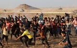 Palestinians run from tear gas fired by Israeli security forces along the border fence, east of Khan Younis in the southern Gaza Strip, on August 25, 2021. (Mahmud Hams/AFP)