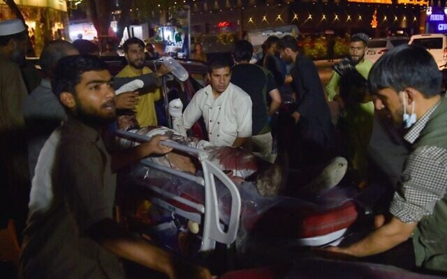 Volunteers and medical staff bring an injured man on a stretcher for treatment after two powerful explosions, which killed at least six people, outside the airport in Kabul on August 26, 2021. (Wakil KOHSAR / AFP) Volunteers and medical staff bring an injured man on a stretcher for treatment after two powerful explosions, which killed at least six people, outside the airport in Kabul on August 26, 2021. (Wakil KOHSAR / AFP)