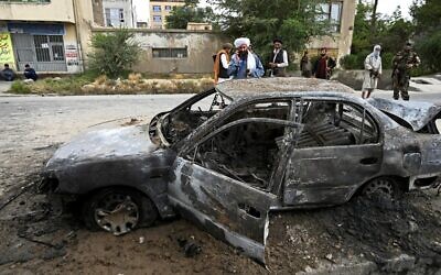 Taliban fighters investigate a damaged car after multiple rockets were fired in Kabul on August 30, 2021.  (Wakil Kohsar / AFP)
