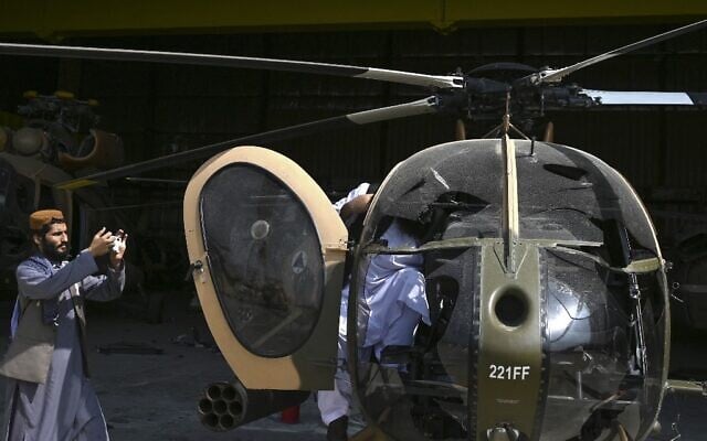 A Taliban fighter takes a picture of a damaged Afghan Air Forces MD 530 helicopter with his mobile phone near the hangar at the airport in Kabul on August 31, 2021 (WAKIL KOHSAR / AFP) A Taliban fighter takes a picture of a damaged Afghan Air Forces MD 530 helicopter with his mobile phone near the hangar at the airport in Kabul on August 31, 2021 (WAKIL KOHSAR / AFP)