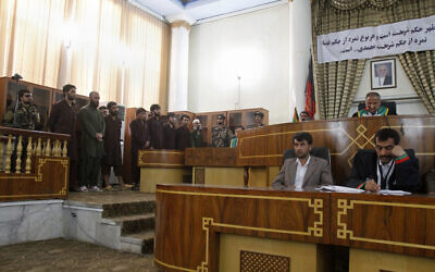 Defendants attend a trial at the Primary Court in Kabul, Afghanistan, on May 6, 2015. The sign in Dari behind the judges reads, "verdicts are based on Sharia (law), any rebellion against the verdict is rebellion against (the Prophet) Muhammad." (AP/Allauddin Khan)